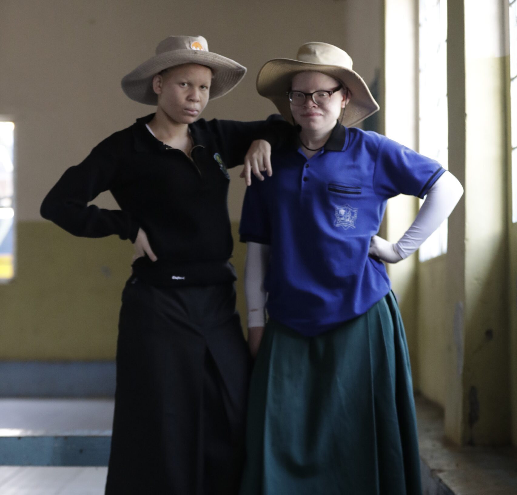 Two girls with albinism standing along the school corridor