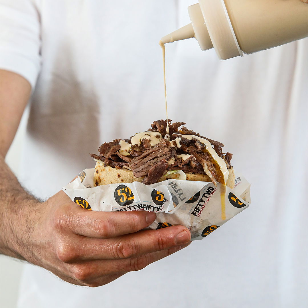 פיתה שווארמה בחיפה עם טחינה סלטים טריים ובשר חם שזה עתה נחתך מהשיפוד