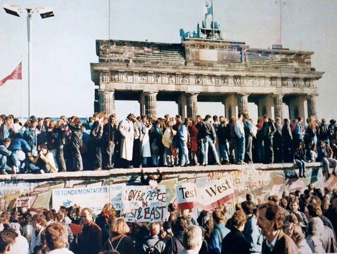 East and West Germans at the Berlin Wall in 1989. Overshadowed by the Brandenburg Gate