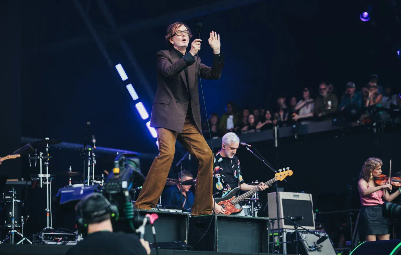  Members of the Britpop band Pulp stand together in a group portrait from their 2025 reunion tour, which coincided with the release of their eighth studio album, More. From left to right, the members are Mark Webber (guitar), Candida Doyle (keyboards), Jarvis Cocker (lead vocals), and Nick Banks (drums). The 2025 iteration of the band is an expanded nine-piece, featuring touring members Andrew McKinney on bass, Emma Smith on violin, and Adam Betts on multiple instruments including percussion and keyboards. This tour included a high-profile "secret" set at the 2025 Glastonbury Festival under the pseudonym "Patchwork," where the band performed career-spanning hits alongside new tracks like "Spike Island" and "Got To Have Love".