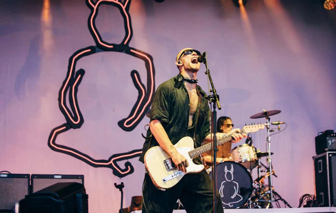Wunderhorse performing live at The Park stage during Glastonbury 2025, featuring the lead singer singing intensely into a microphone.