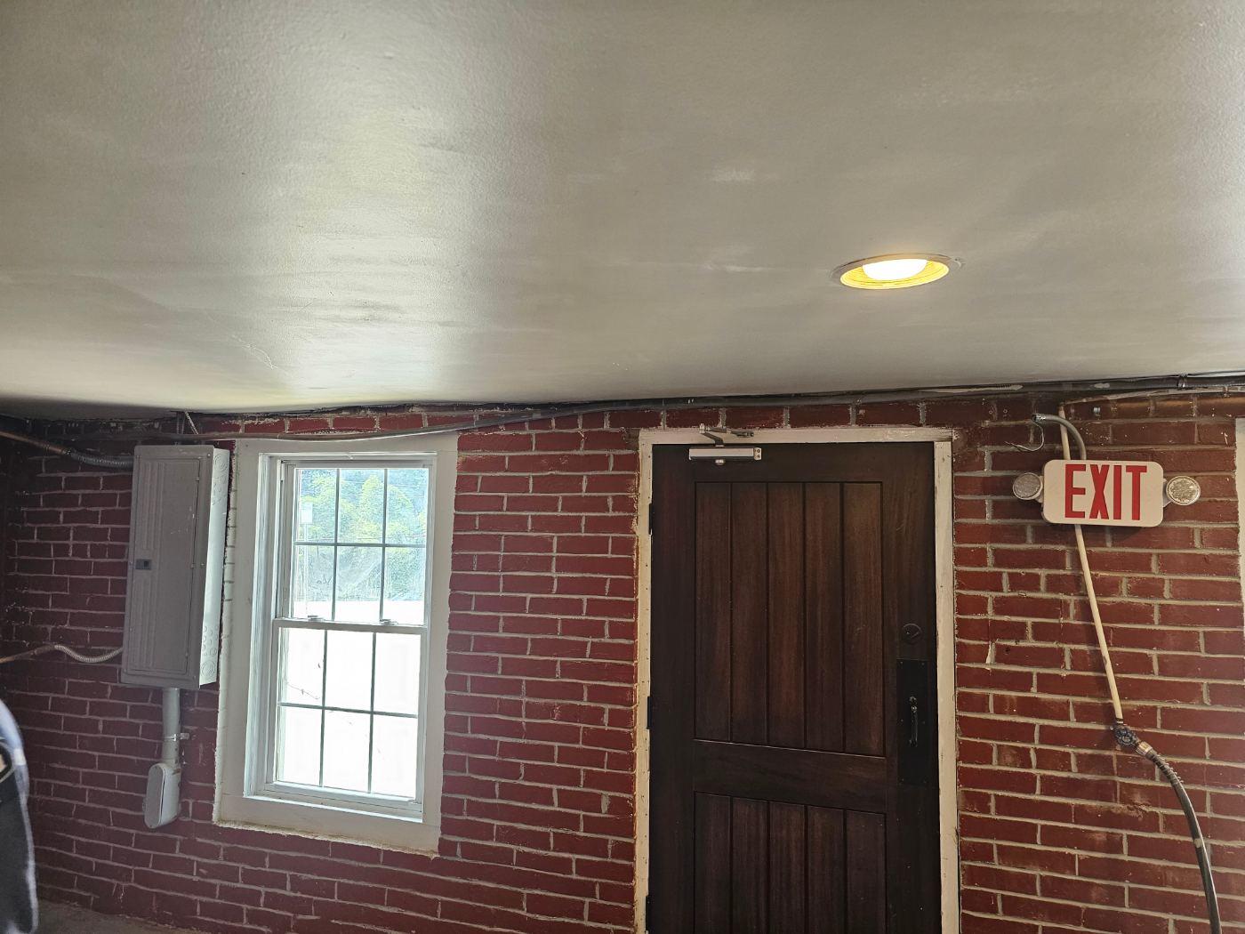 Finished brick basement with recessed lighting and exit sign wired by Stickler’s Electrical Service, electrician serving Cajah’s Mountain, NC