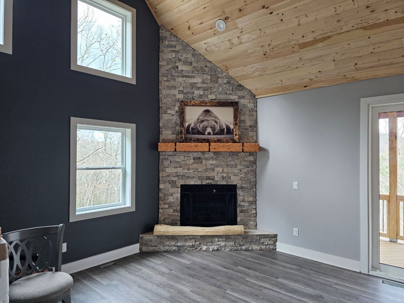 Living room with stone fireplace and wood ceiling lighting by Stickler’s Electrical Service, electrician serving Glen Alpine, NC