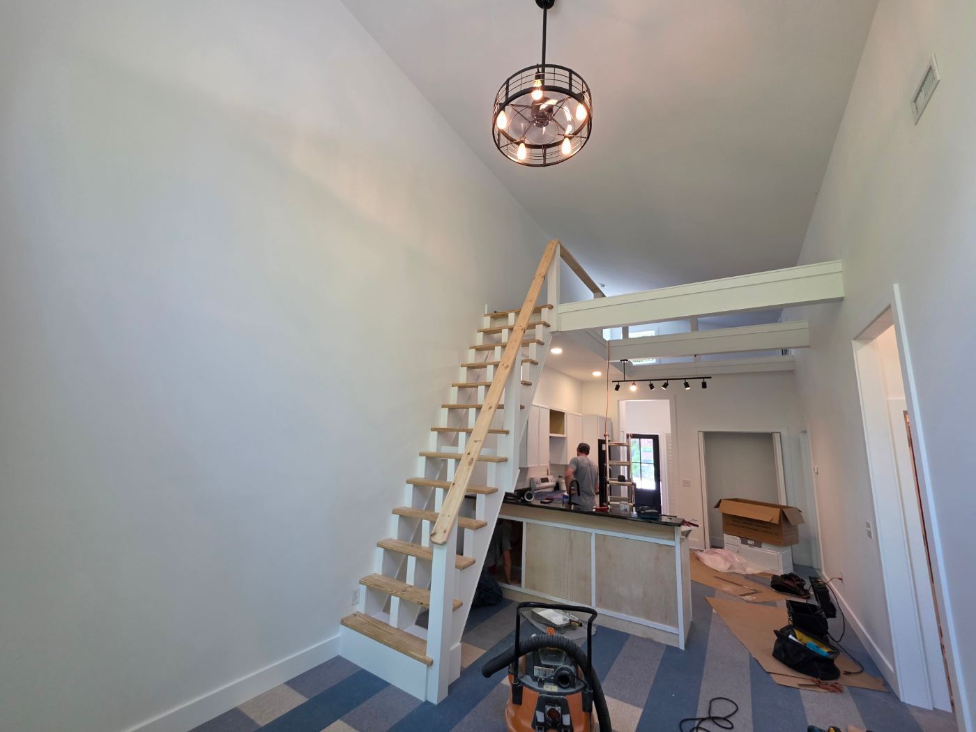 Finished living area with a loft stair, pendant light and track lighting in a new duplex near Morganton, NC