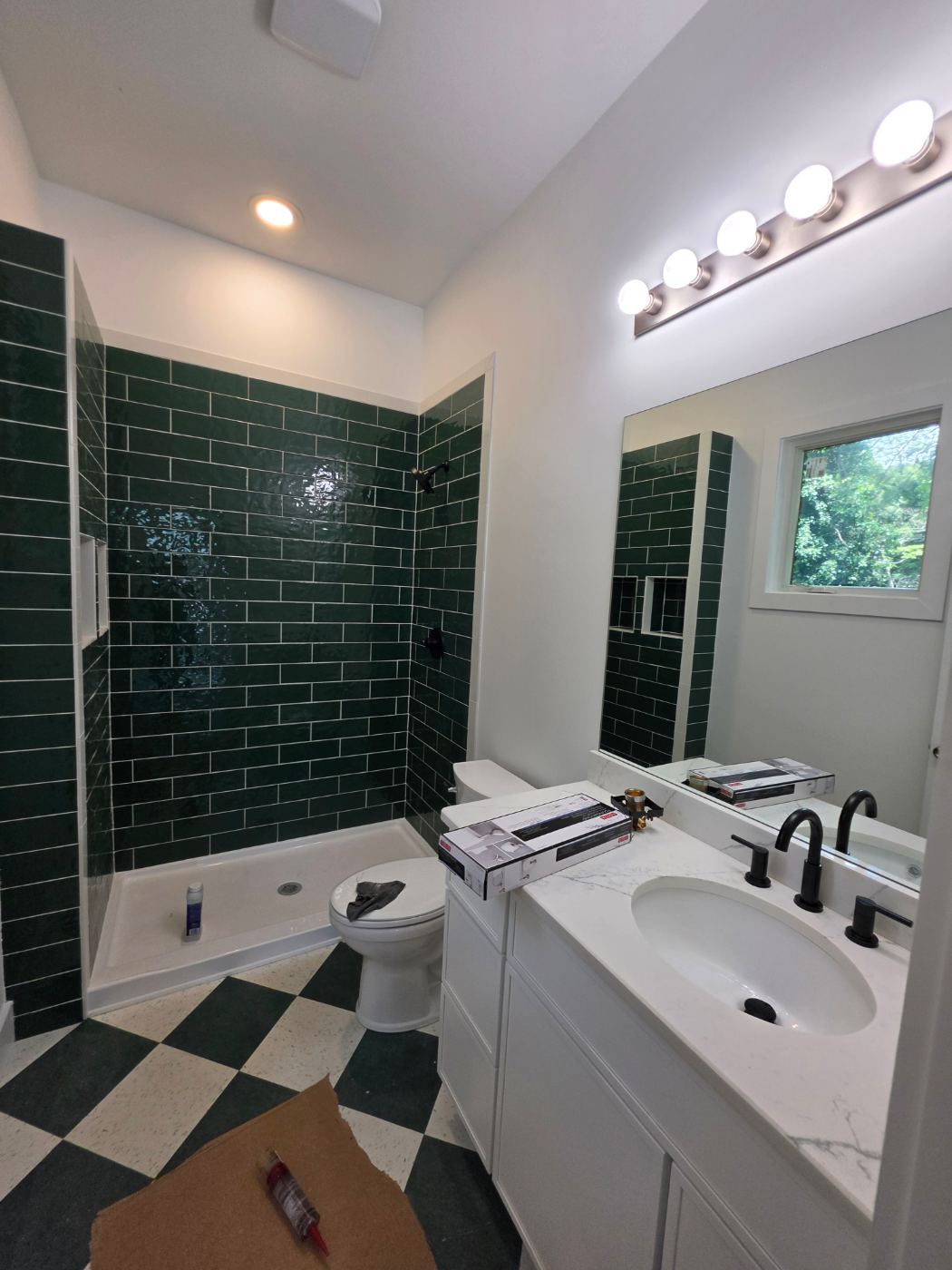 Green tile bathroom with vanity light, recessed light and exhaust fan in a new duplex near Morganton, NC