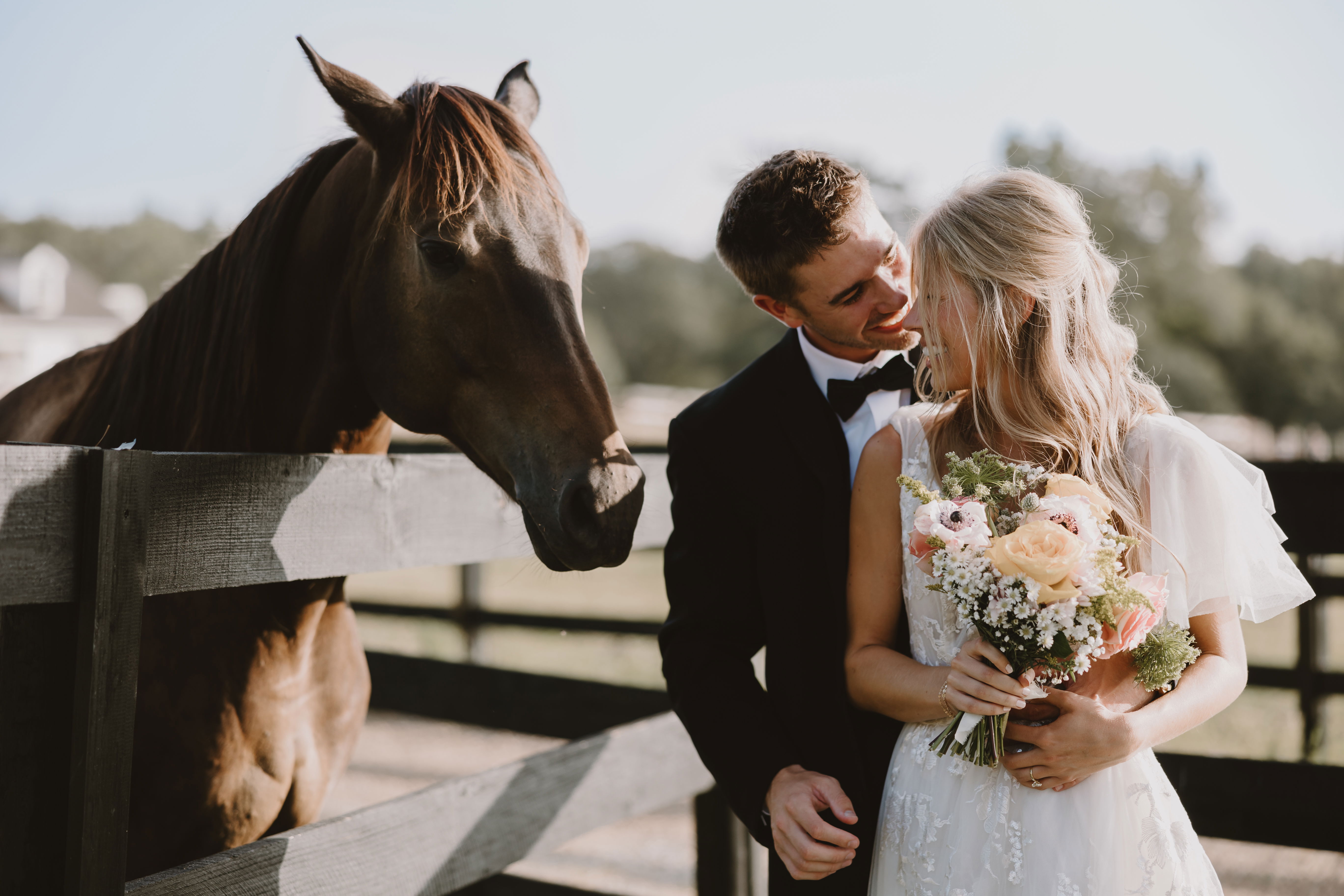 couple gazing into each others eyes during wedding photography in rustic elegant location with stable and horses