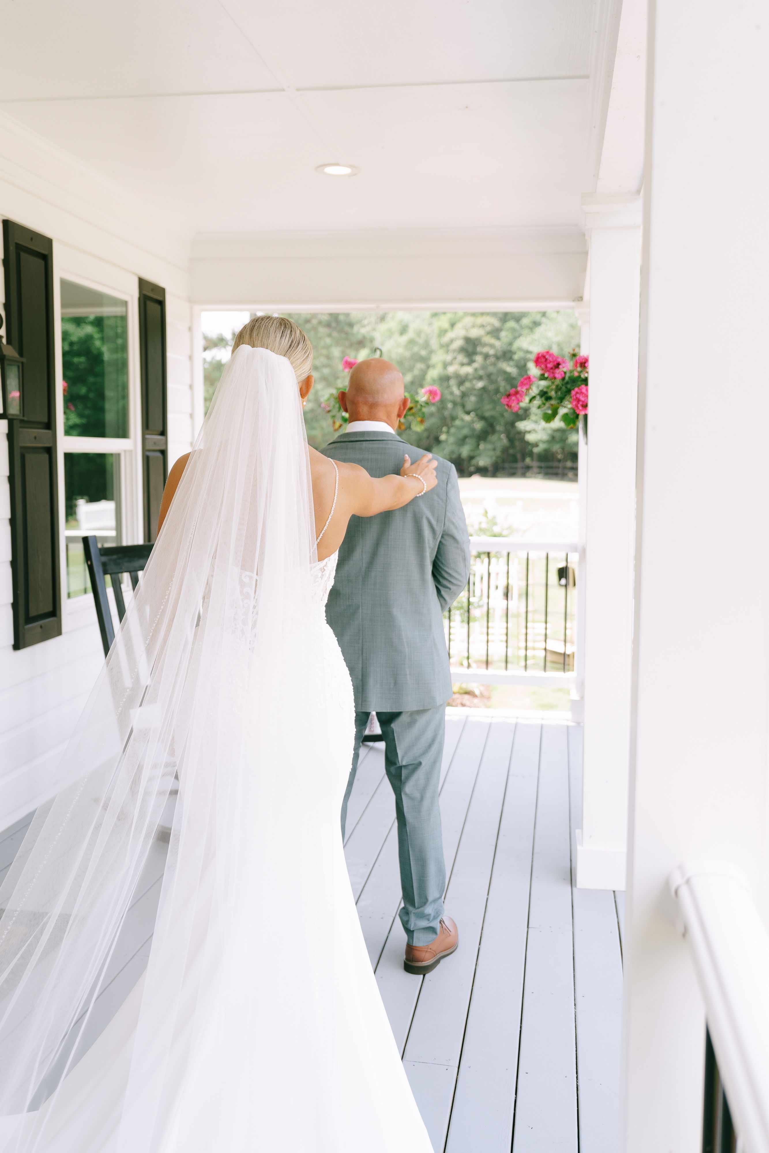 beautiful bride having first look with father on cottage porch with rocking chairs and flowers in Walton County, Georgia, near Barrow County, GA