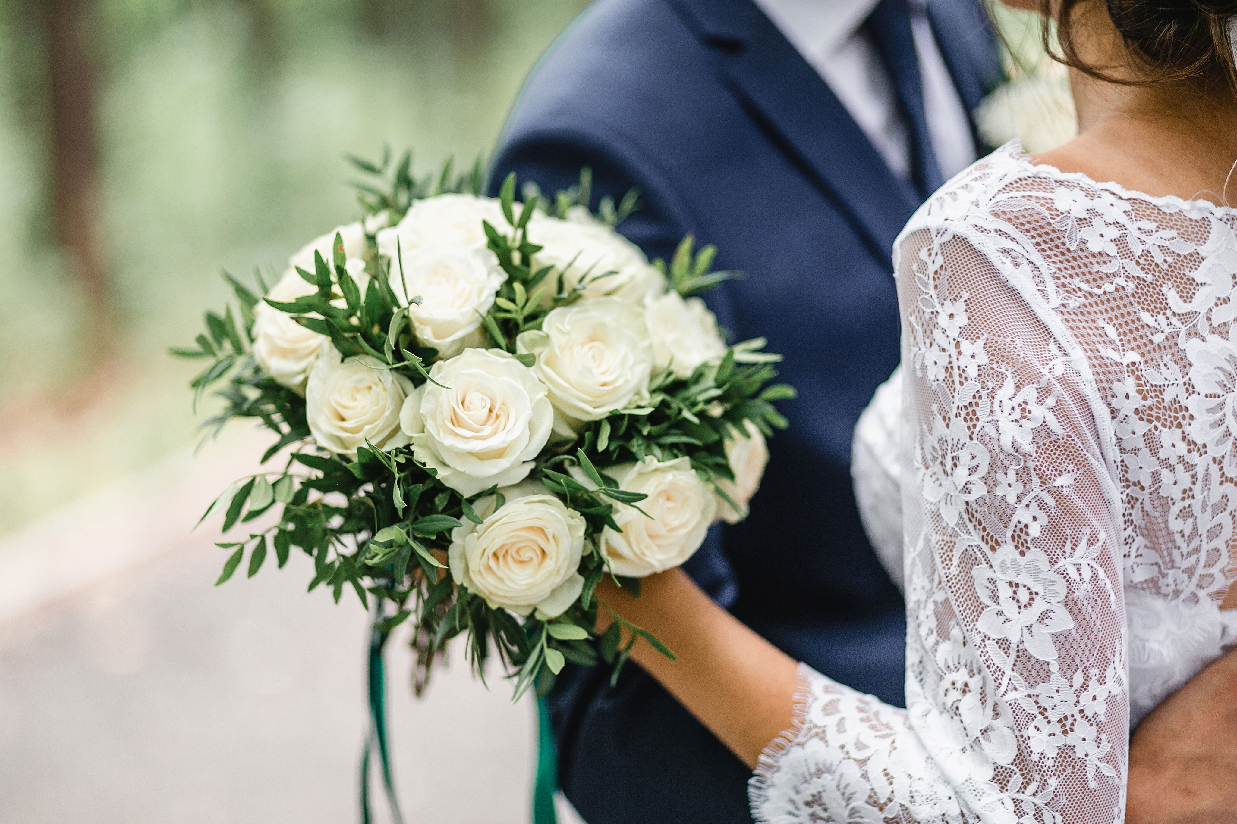 florist provided bridal bouquet of fresh florals as groom and bride embrace for wedding photography after the outdoor ceremony