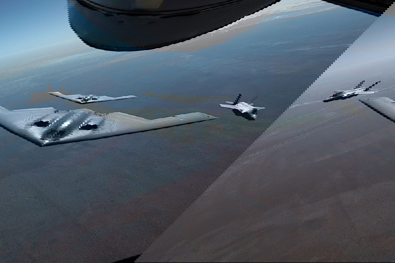 B2 Spirit bomber flanked by F-22 Raptors and F-35s.
