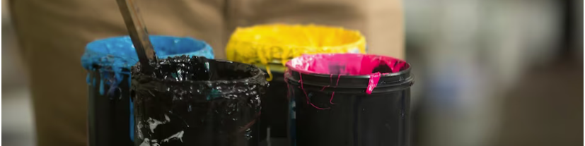 Quatre pots de peinture : noir, jaune rose, bleu