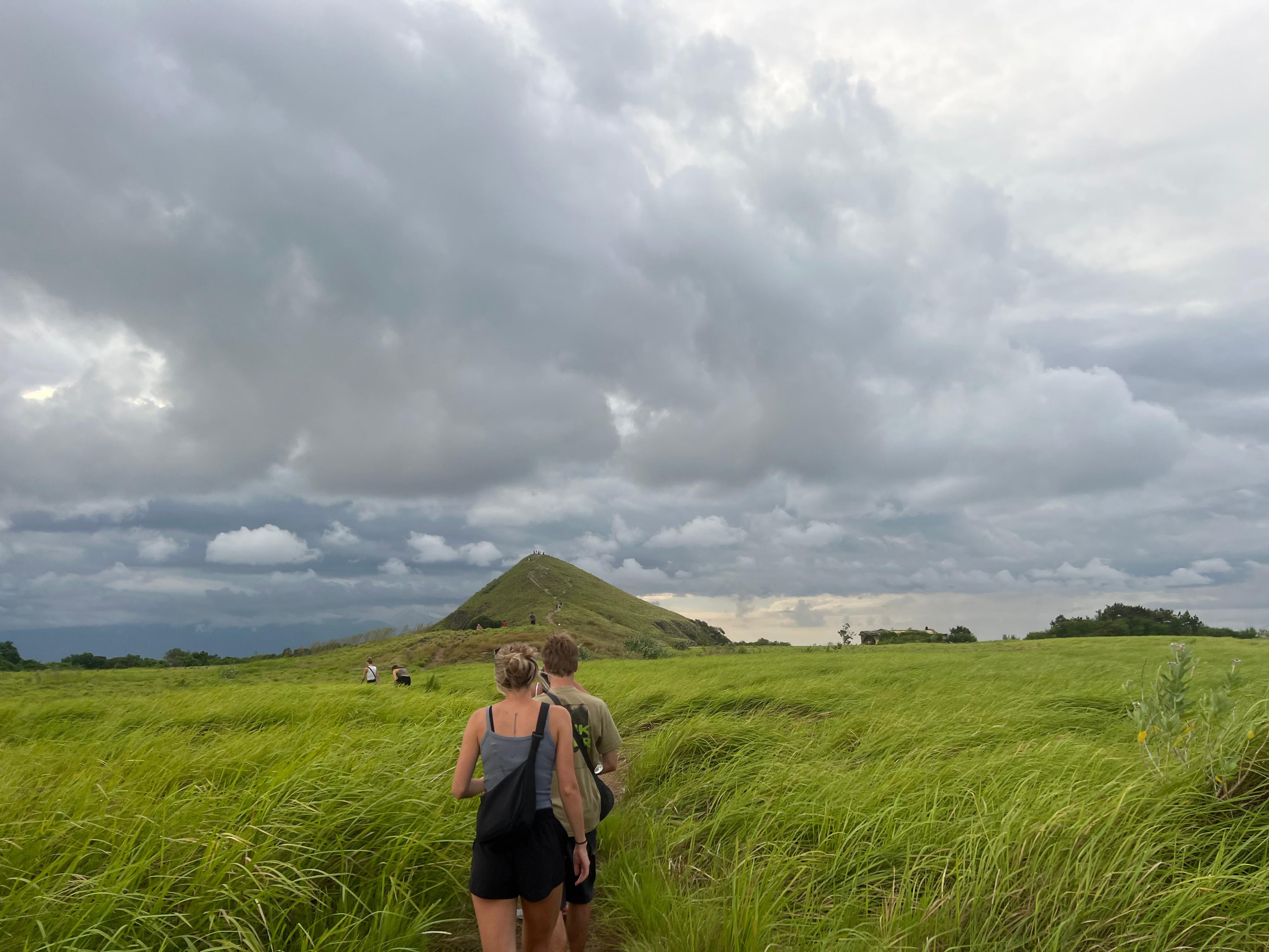 A group of tourists walking on the trail toward Kenawa Island hill during the lush green season
