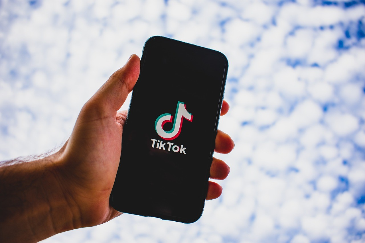 man holding phone with tiktok open below the sky background