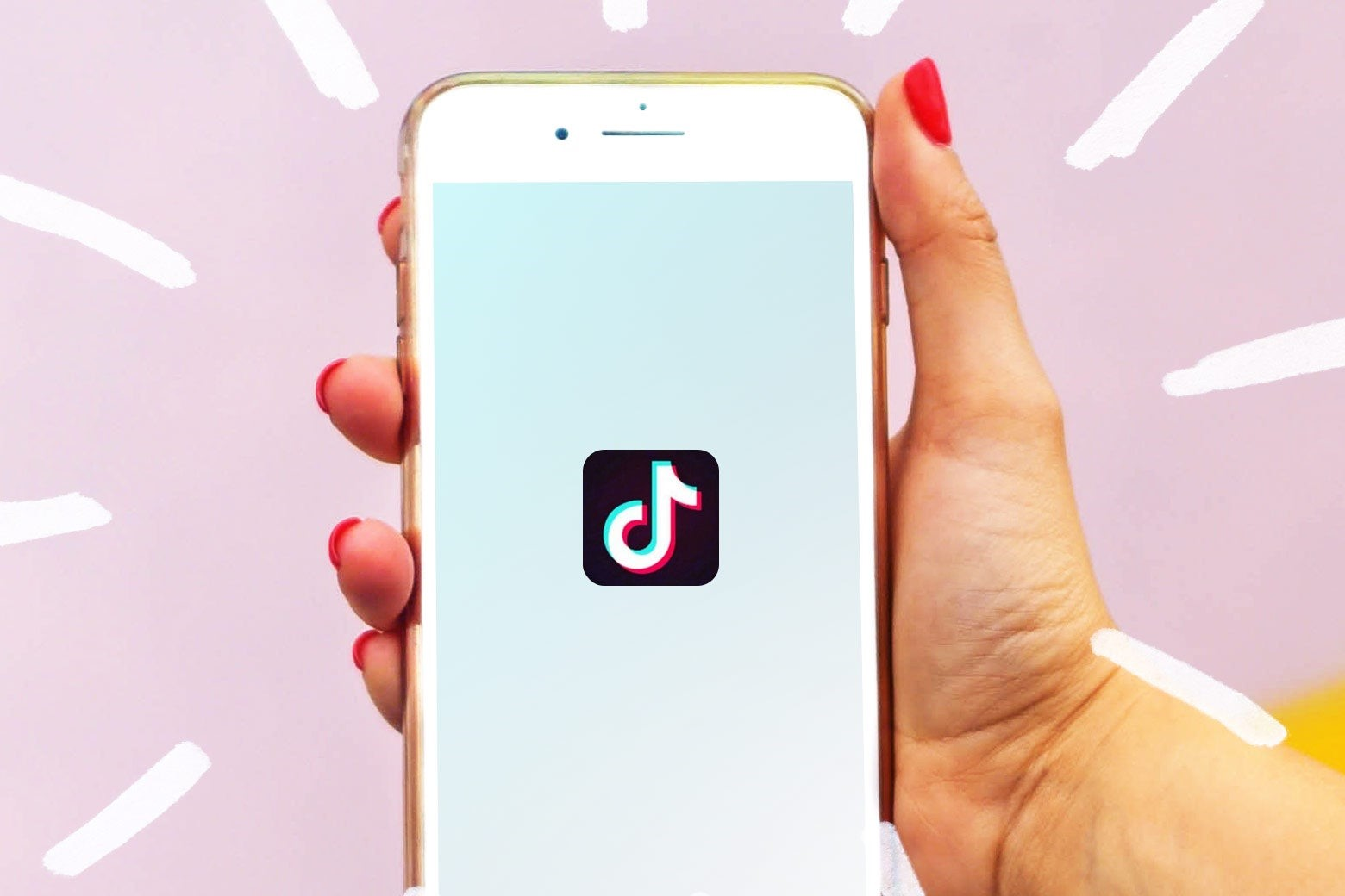 woman holding phone with tiktok open in front of pink background