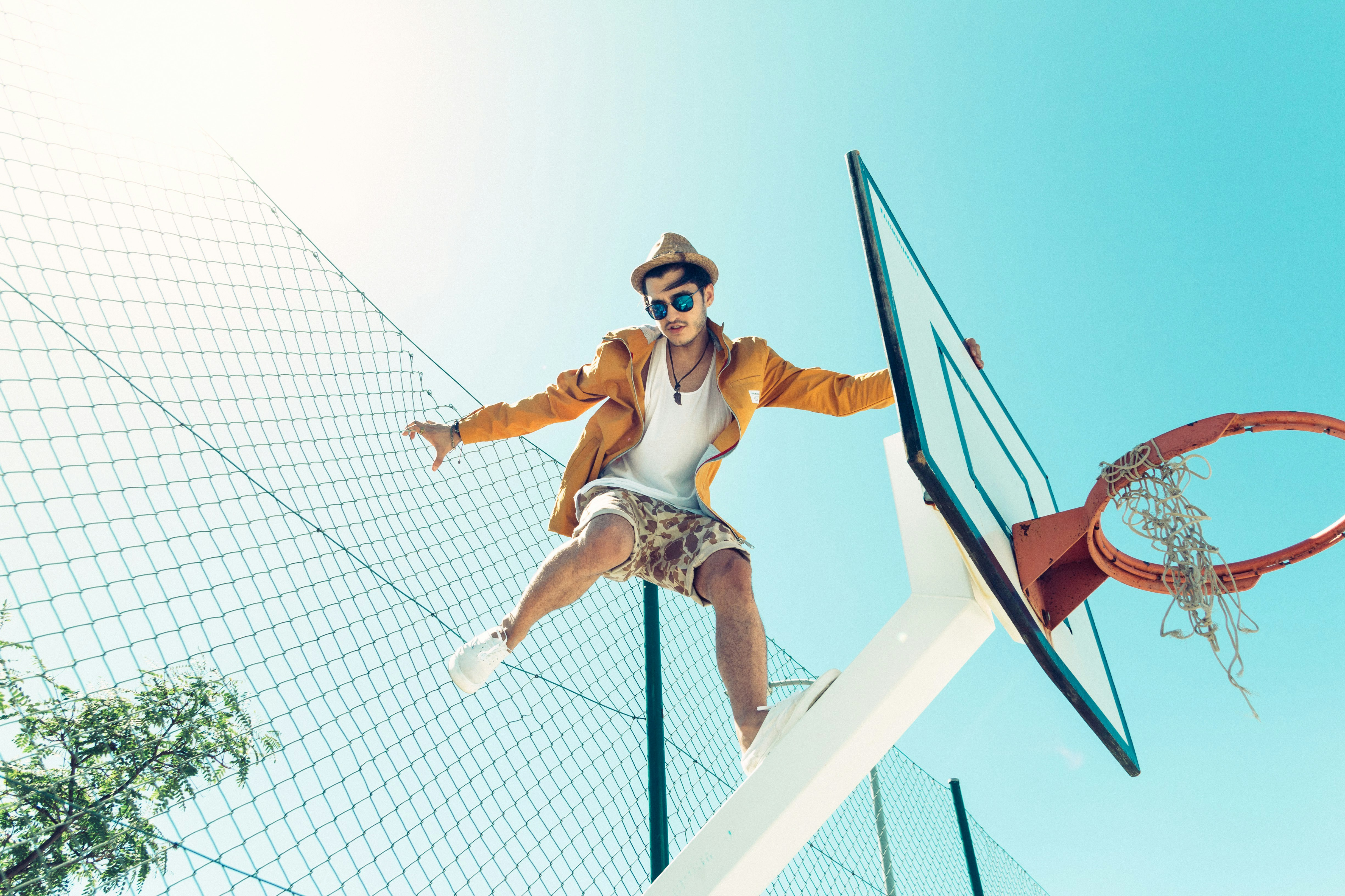 man standing on basketball hoop system stand during daytime