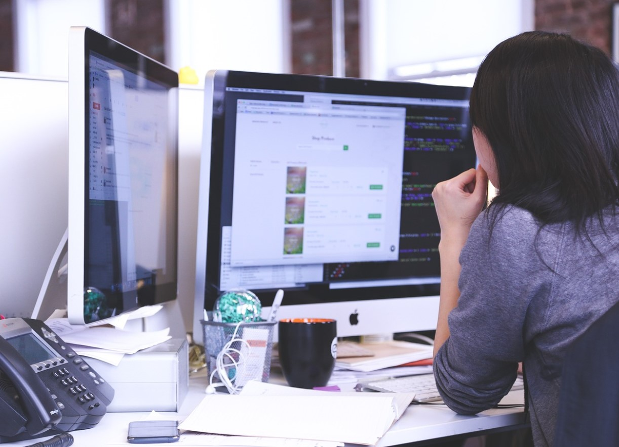 woman sitting in desk looking at macbook