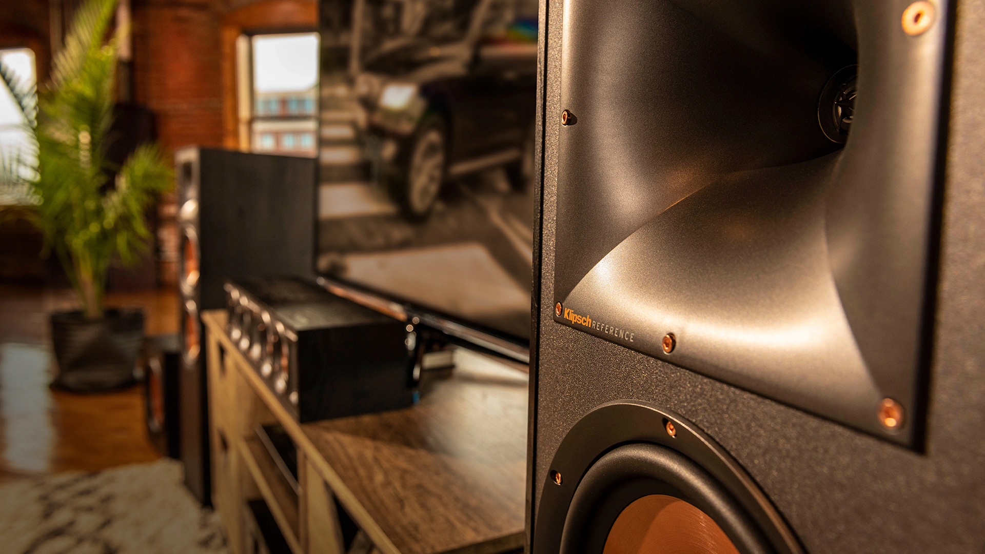 תמונת אווירה של הרמקולים הרצפתיים Klipsch R-620F יחד עם רמקול סנטר תואם על שידת עץ בסלון