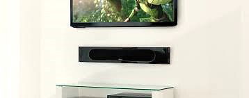 רמקול Monitor Audio Radius One תלוי על קיר מתחת לטלויזיה