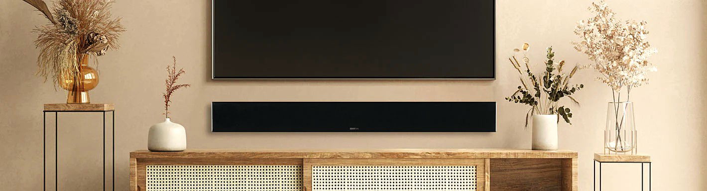 תמונת אווירה של הסאונדבר מוניטור אודיו monitor audio sb-4 תתלוי מתחת לטלויזיה ומעל שידה חומה בסלון