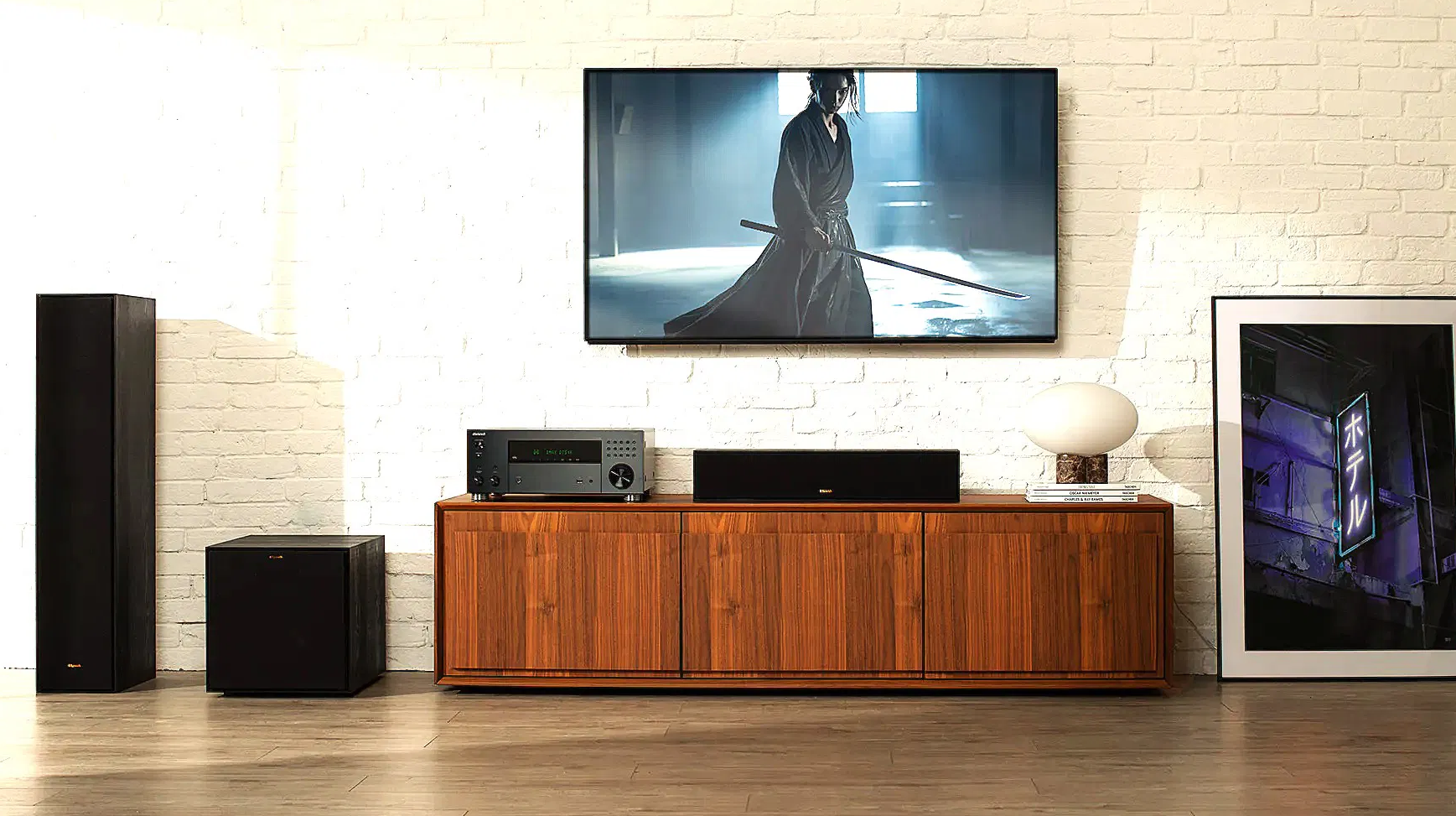 תמונת אווירה של הרסיבר אונקיו onkyo txrz30 מונח על שידת עץ עם טלויזיה ורמקולים מסביב