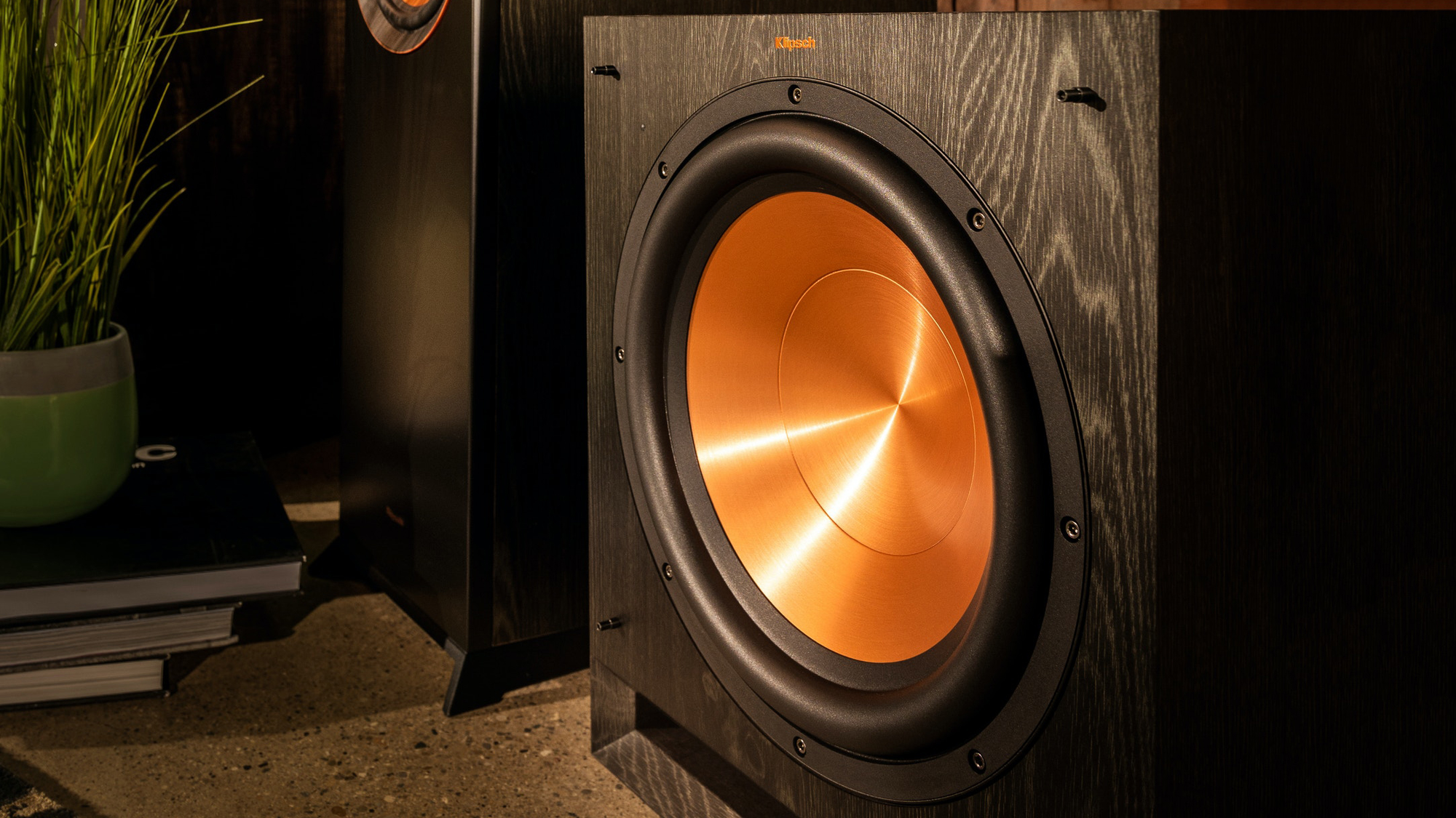 תמונת אווירה של הסאב האקטיבי של קליפש klipsch spl-150 מונח על הרצפה על יד רמקול רצפתי תואם כחלק ממערכת