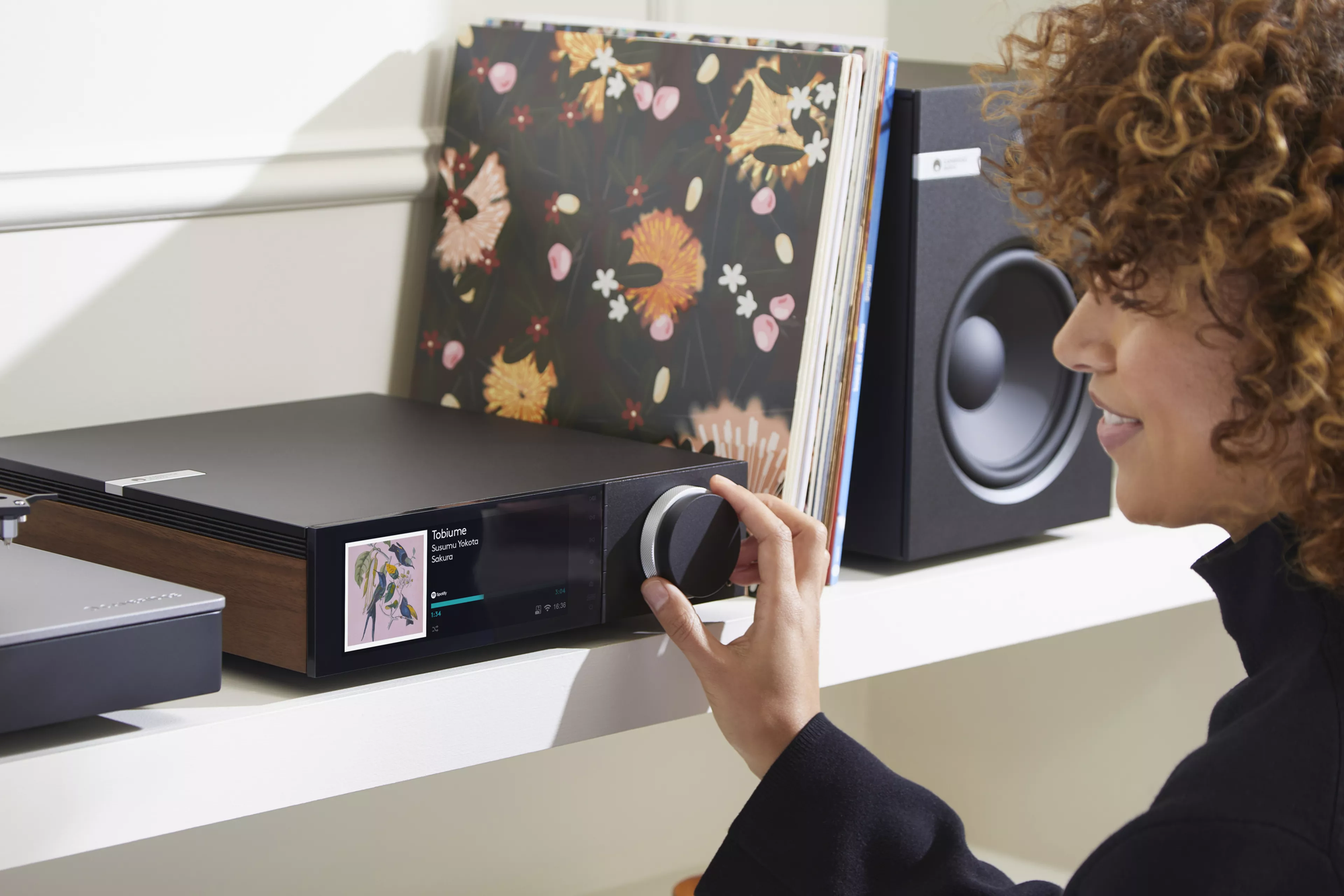 בחורה מפעילה את המגבר רסיבר סטרימר היי אנד קמברידג' אודיו Cambridge Audio EVO 150 בצילום מלמעלהמגבר רסיבר סטרימר היי אנד קמברידג' אודיו Cambridge Audio EVO 150 בנגיעה בכפתור הווליום