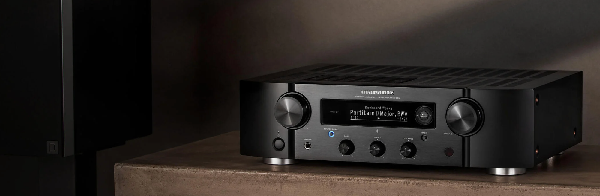 מגבר עם סטריאו סטרימר חכם Marantz PM7000N מצולם יושב על שידת עץ