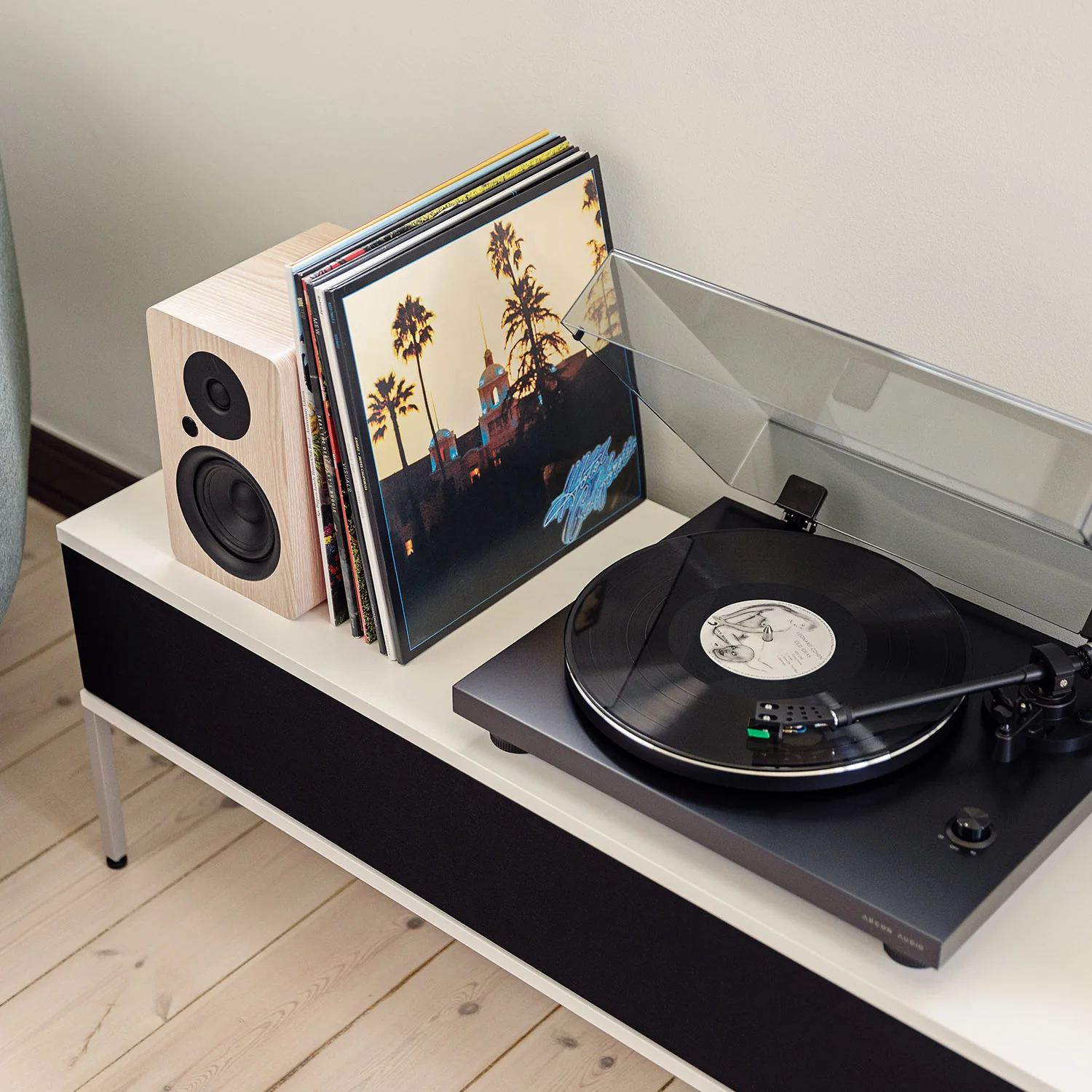 פטיפון ארגון Argon Audio TT-3 בגימור לבן בצילום מלמעלה מונח על שידה עם זוג רמקולים מדפיים משני הצדדים