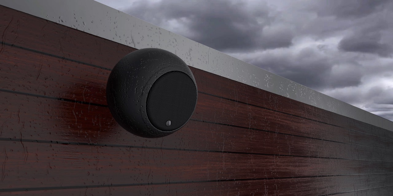 רמקול גאלו Gallo Acoustics Adiva Habitat בצבע שחור תלוי על קיר עץ במרפסת