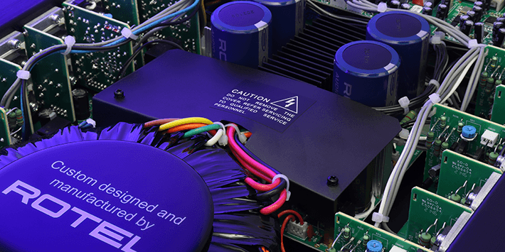 תמונת תקריב של הרכיבים הפנימיים במגבר רב-אזורי Rotel C8, הכוללת טרנספורמר טורואידי עוצמתי להתקנות אודיו יוקרתיות