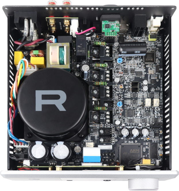 מבט פנימי מלמעלה על רכיבי מגבר Rotel DX-5, המציג שנאי טבעתי (Toroidal) גדול עם לוגו R, קבלי פרימיום ומעגלים אלקטרוניים מורכבים בבנייה קפדנית