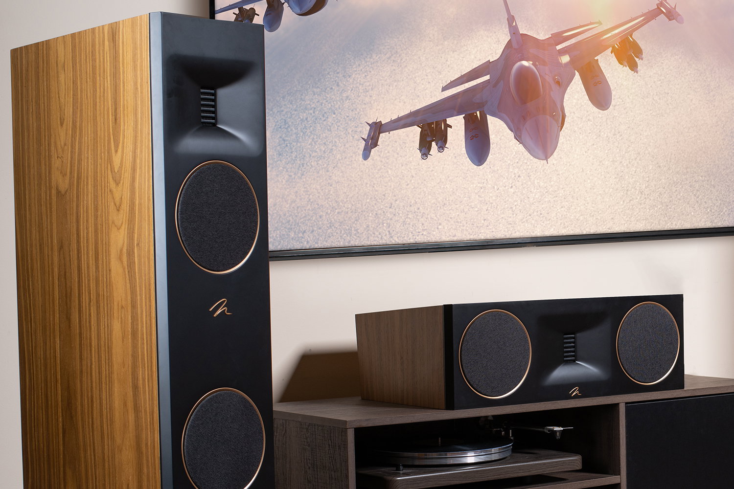 רמקול רצפתי דגל Martin Logan Motion XT F100 בגימור עץ ואלמנטים בזהב, משולב במערכת קולנוע ביתי היי-אנד לצד רמקול סנטר תואם וטלוויזיה המציגה מטוסי קרב