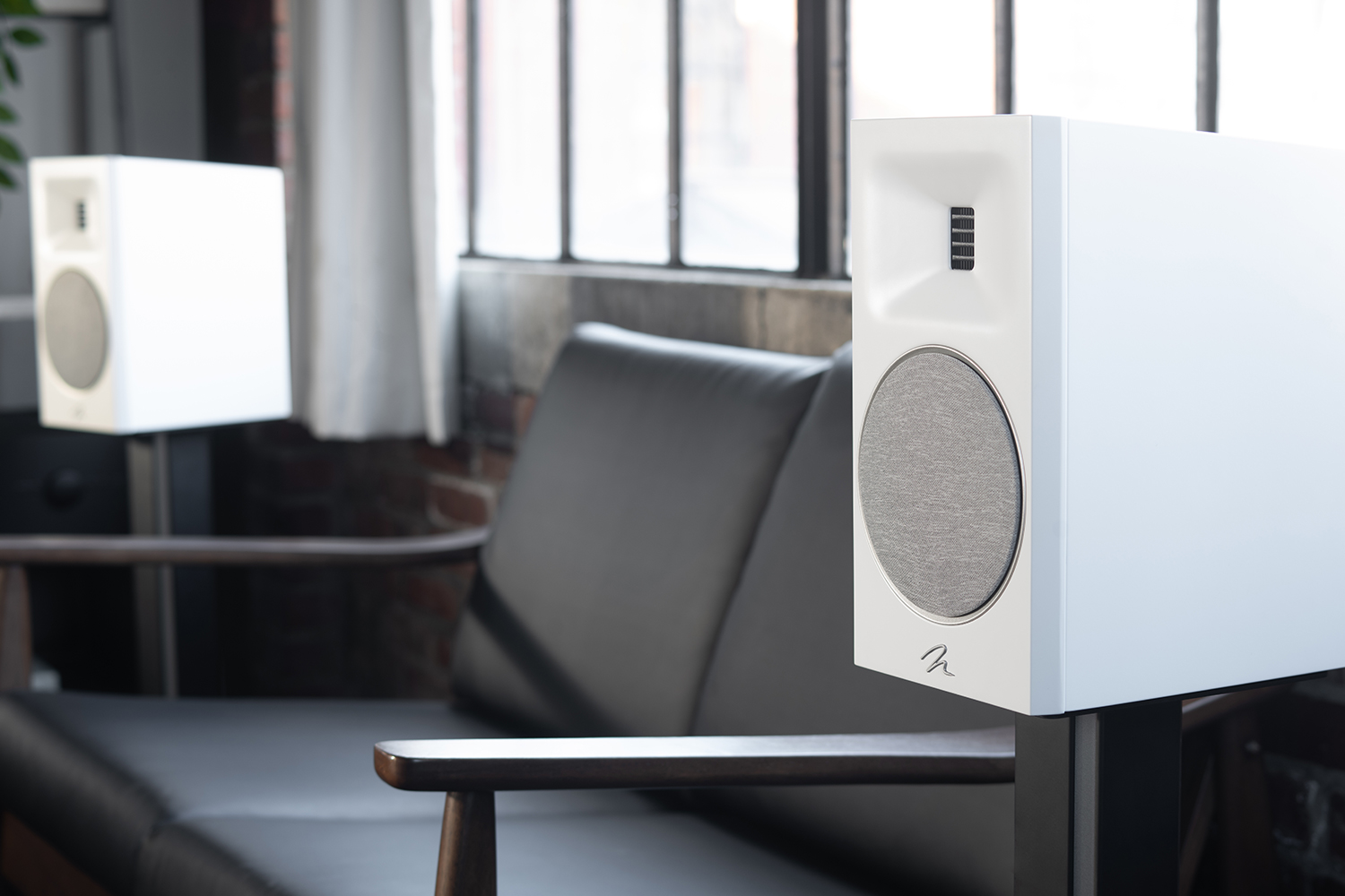 זוג רמקולים מדפיים מרטין לוגן Martin Logan Motion B10 בצבע לבן מונחים על סטנדים משני צידי ספה בסלון