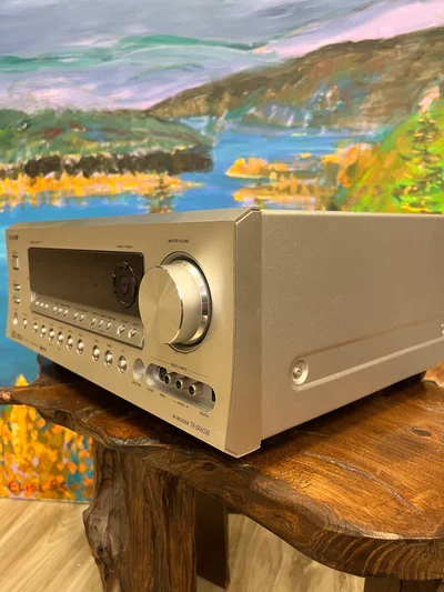 רסיבר קולנוע סטריאו אונקיו בהזדמנות Onkyo TX-SR603 מונח על שרפרף גזע עץ בזוית למצלמה