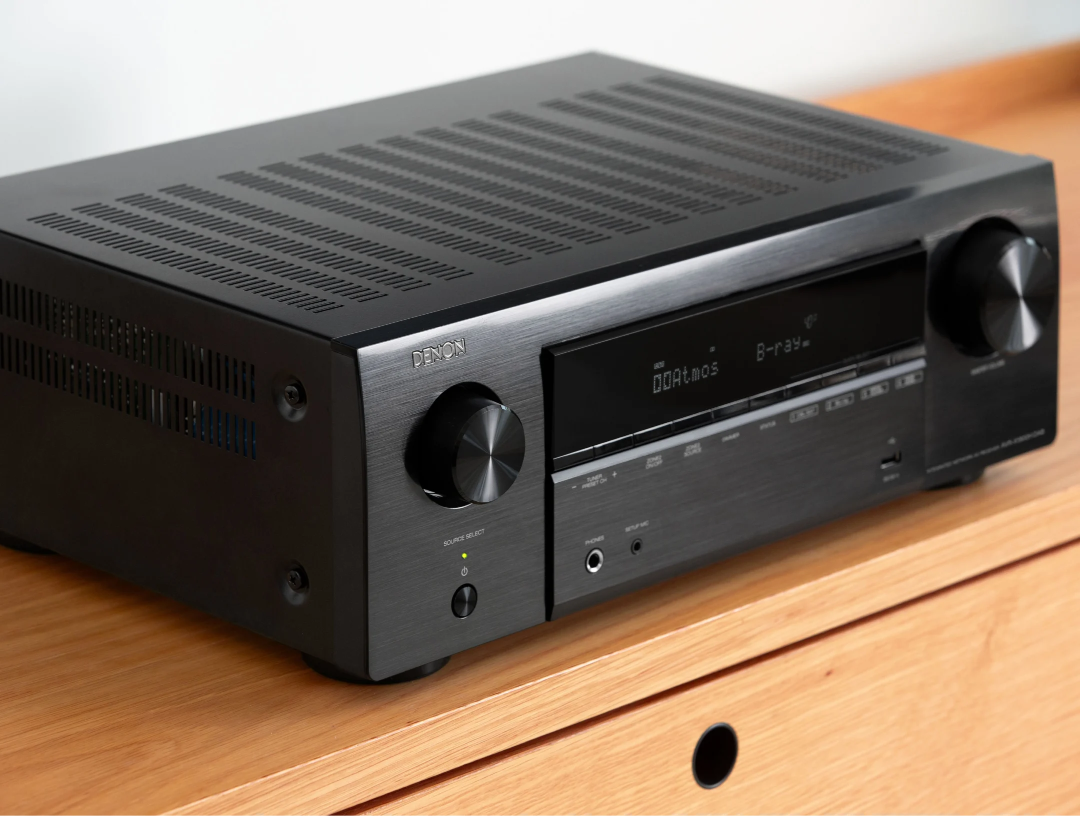 רסיבר קולנוע דנון Denon AVR-X1800H מצולם בזוית מלמעלה ובתקריב מונח על שידת עץ מודרנית ביתית