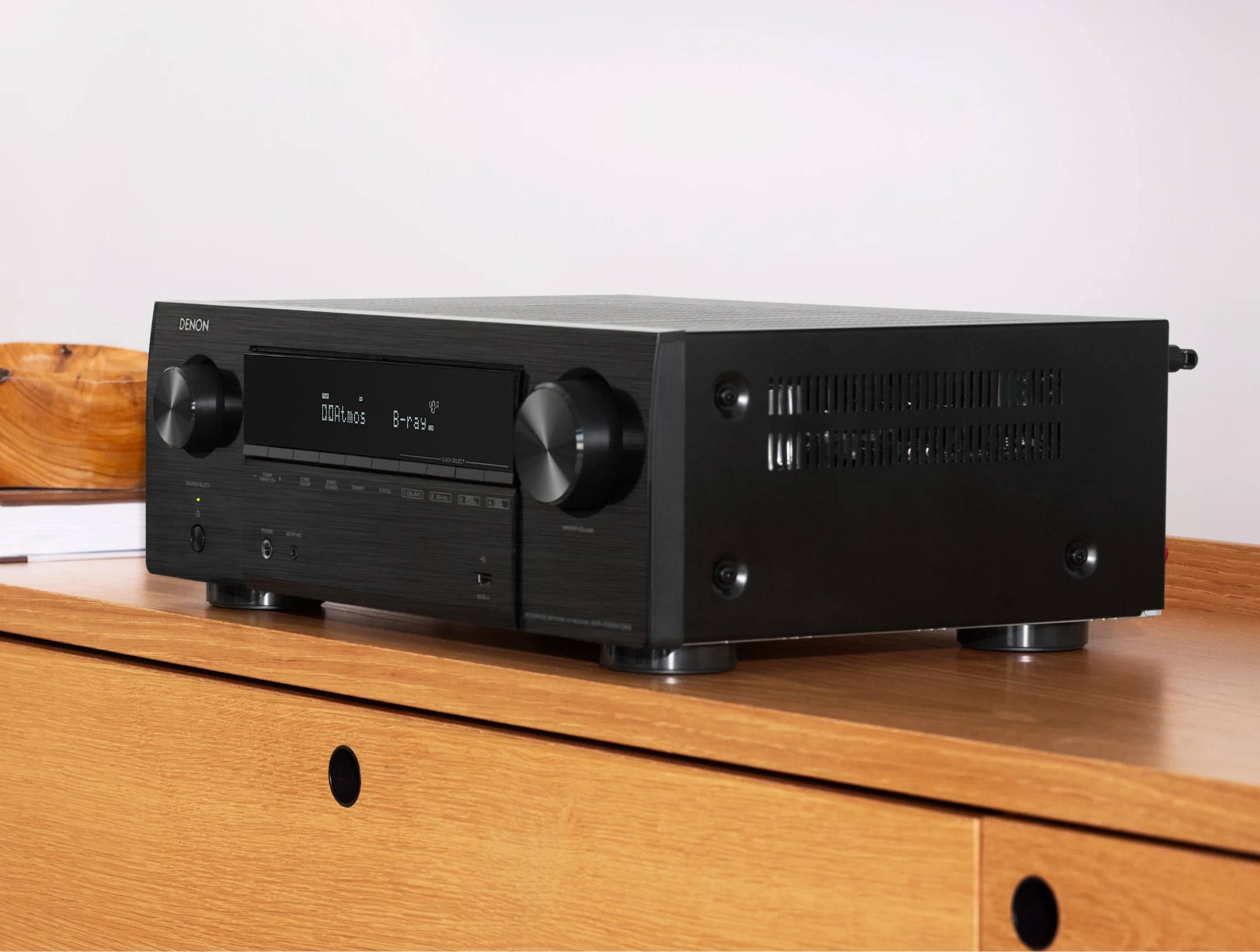 רסיבר קולנוע דנון Denon AVR-X1800H מצולם בזוית מונח על שידת עץ מודרנית ביתית