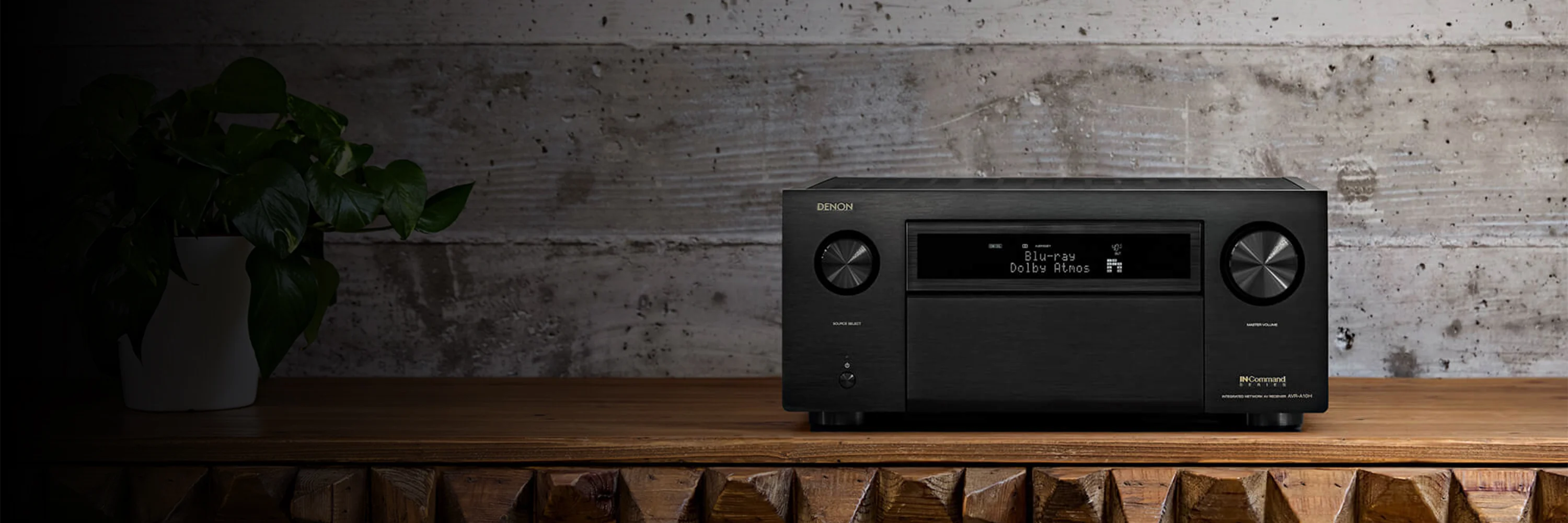 מגבר קולנוע ביתי דנון Denon AVC-A10H בצילום אווירתי מונח על שידת עץ מעוצבת