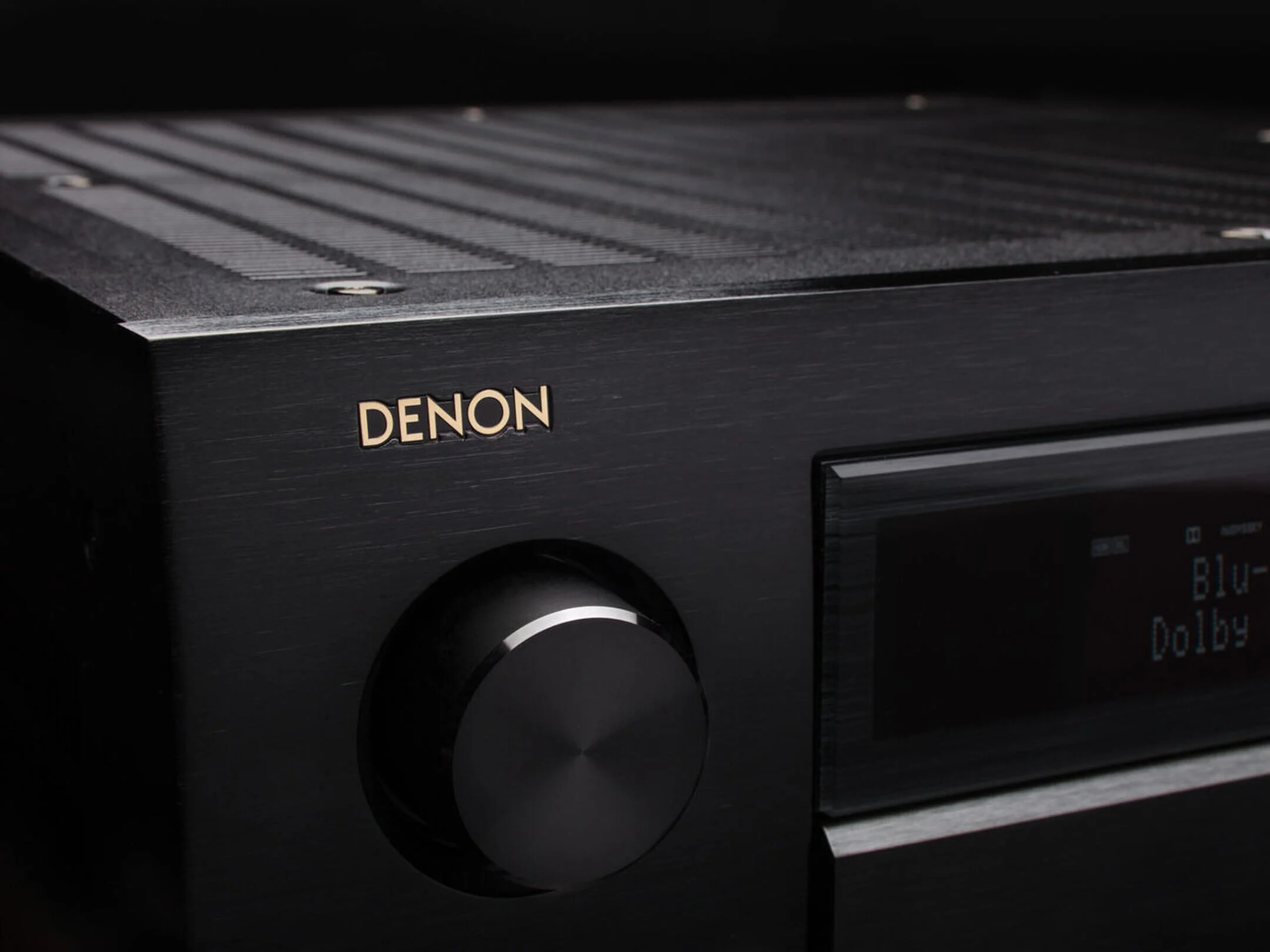 מגבר קולנוע ביתי דנון Denon AVC-A1H צילום תקריב של חלק החזית השמאלי העליון של המגבר עם הלוגו של דנון