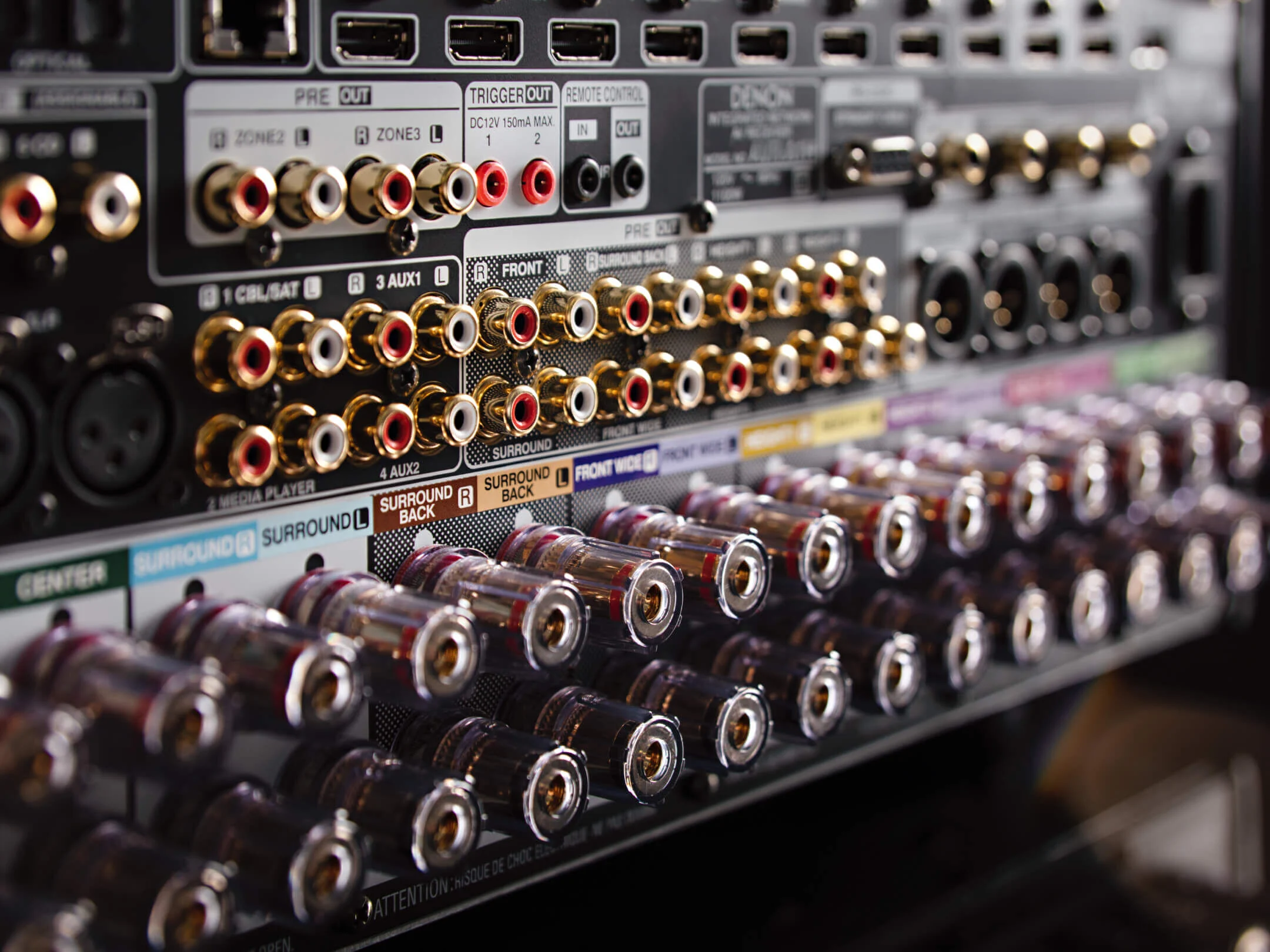 מגבר קולנוע ביתי דנון Denon AVC-A1H בצילום תקריב של חלקו האחורי המצויד בכל חיבורי הקצה מצופי הזהב כולל כניסות ויציאות רמקולים מוזהבים
