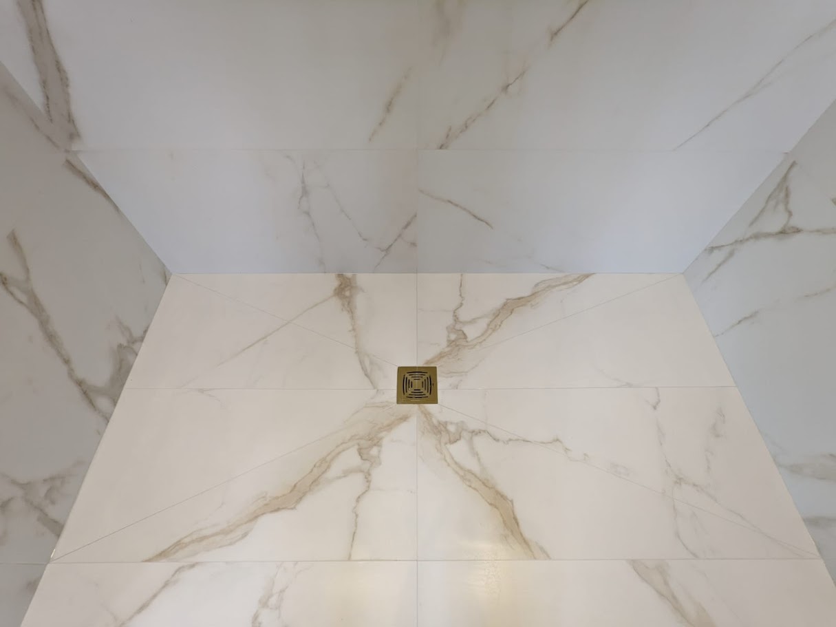 Tiled shower tray, with marble veins flowing to the drain by Hunter Tiling Ltd in Loughton