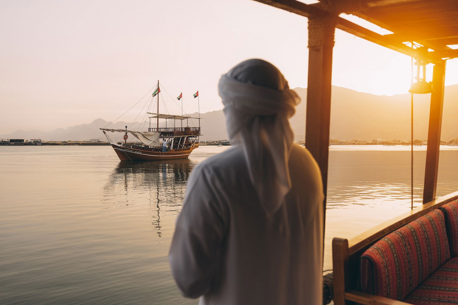 Mann som ser utover sjøen fra en båt, mot en båt, Raz Al Khaimah