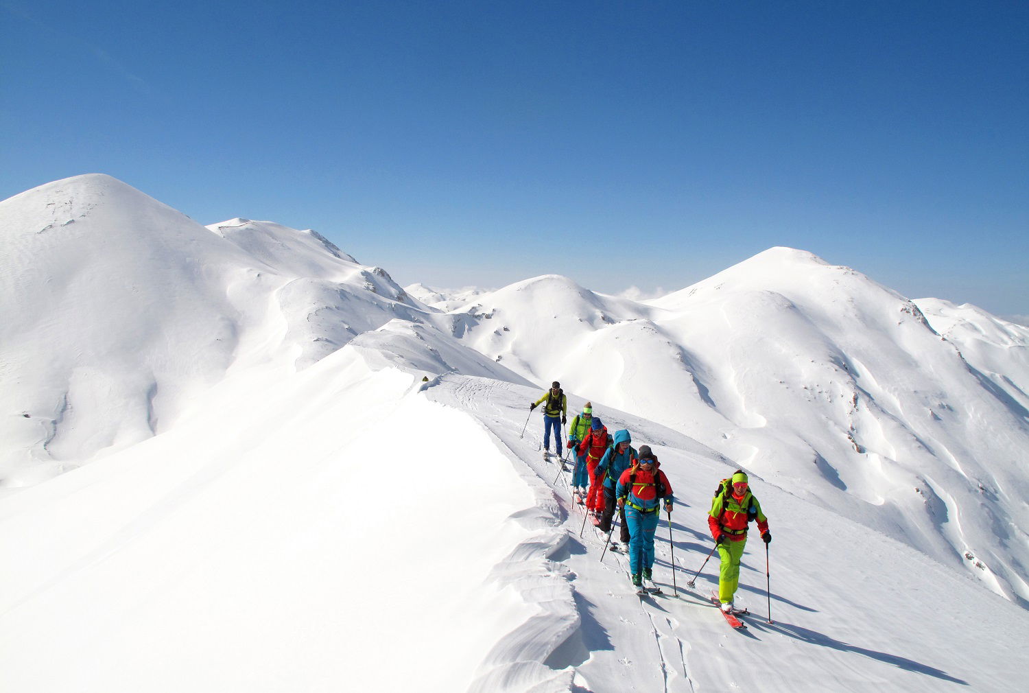 Personer som går på ski i fjellet i snørikt landskap