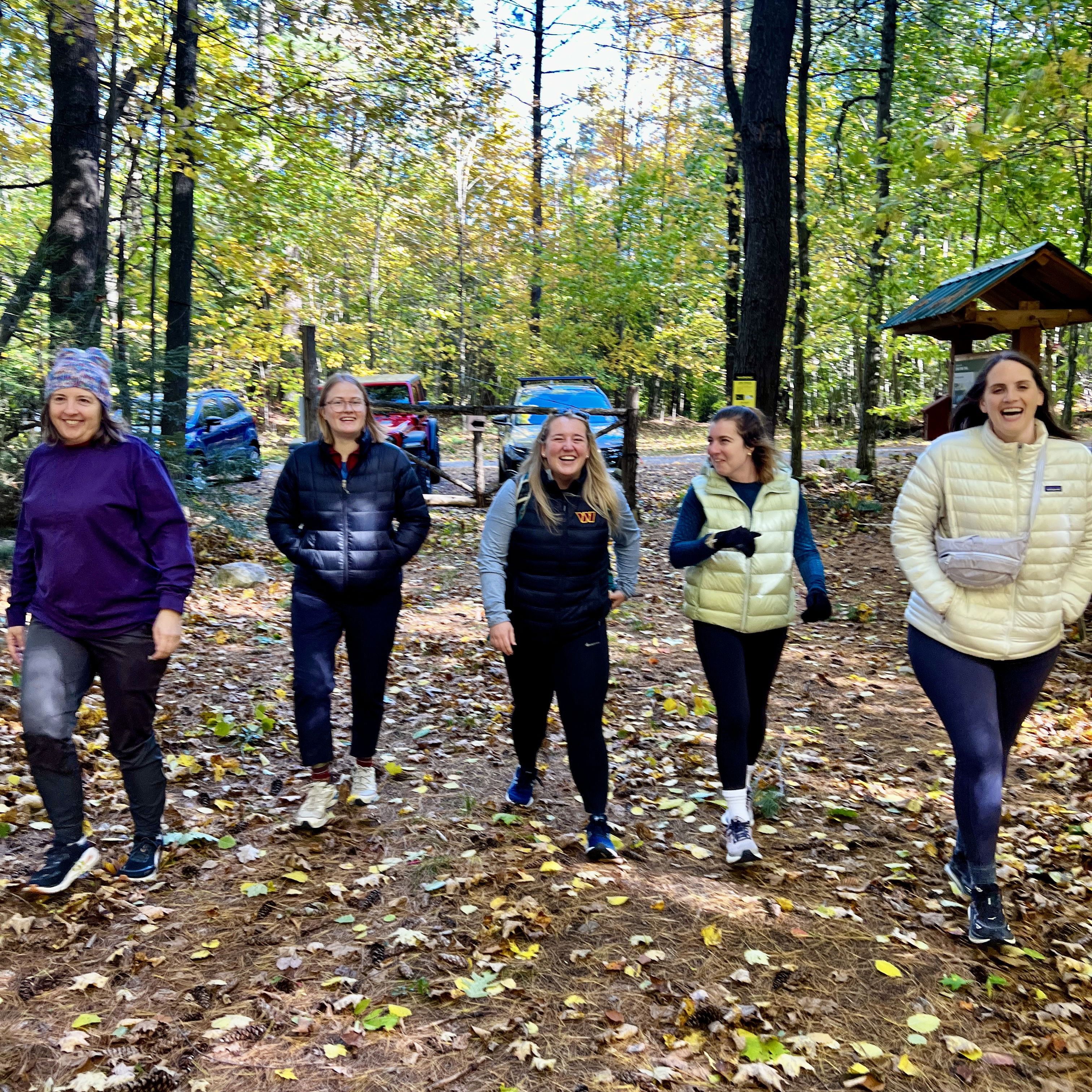 Smiling hikers walk through fall leaves