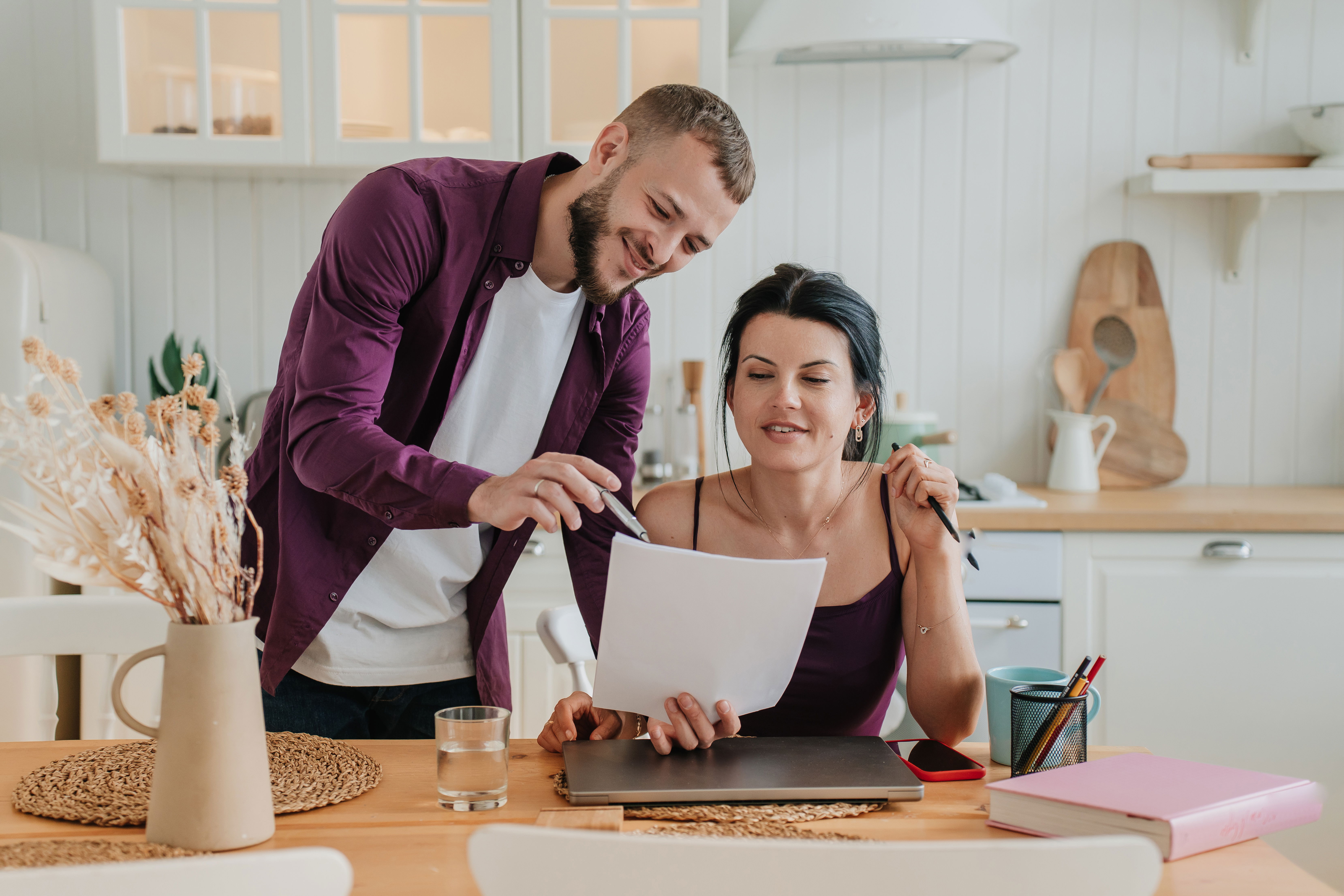 couple at kitchen table planning documents laptop warm natural light