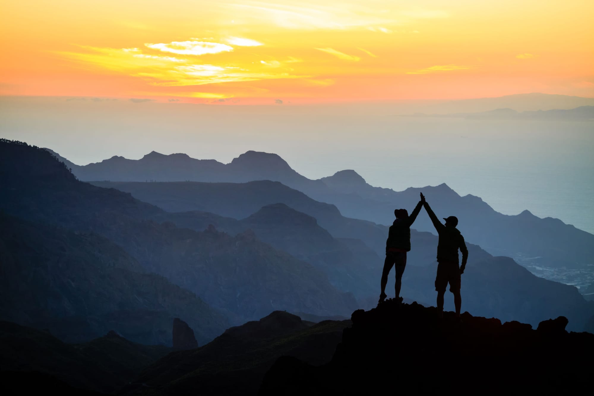 Two people having successfully climbed to the top of the mountain.