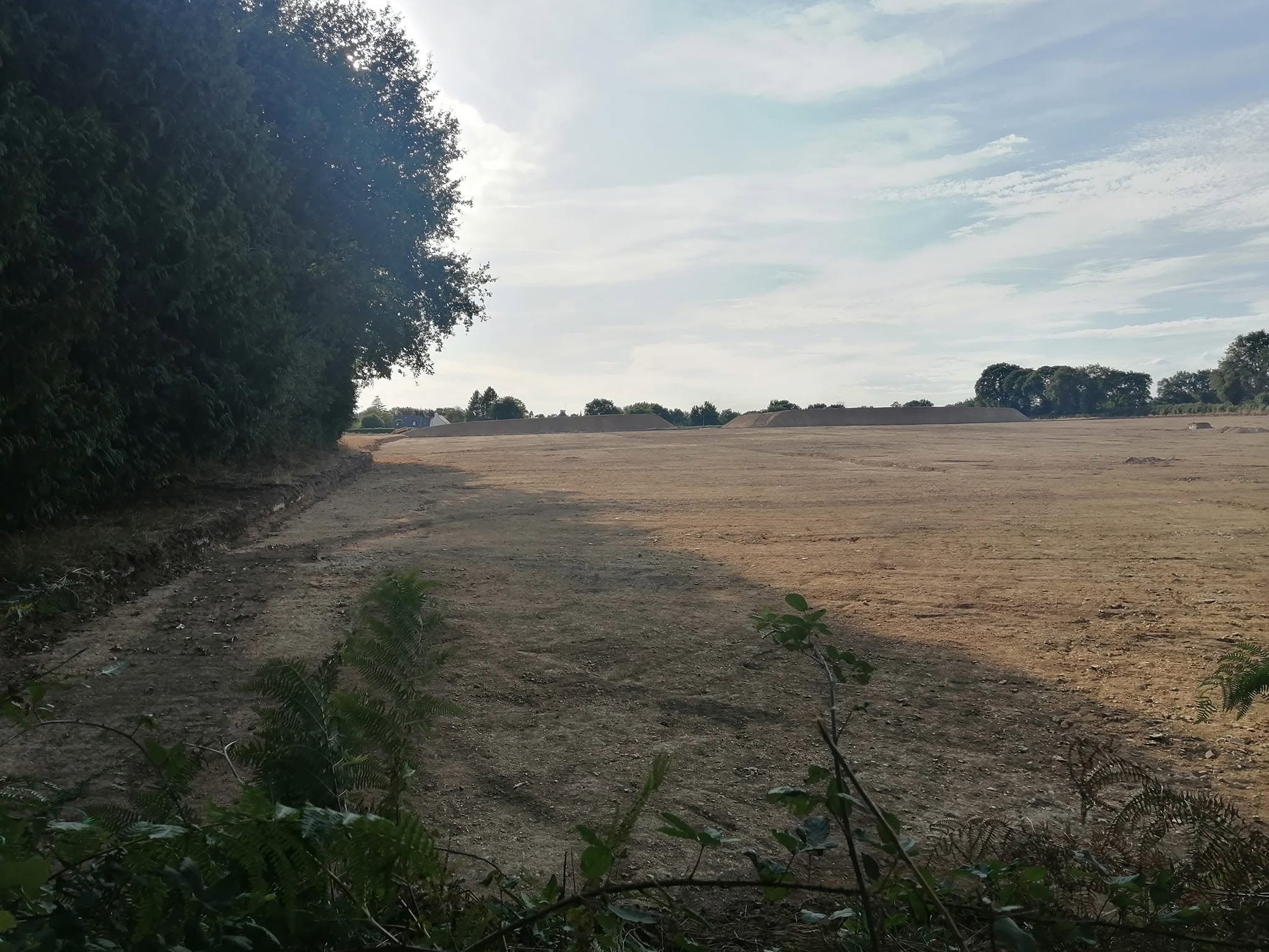 Emplacement du nouveau stade, avant et pendant les travaux, de l’autre côté du bois de Kerozer, par rapport à la longère démolie.