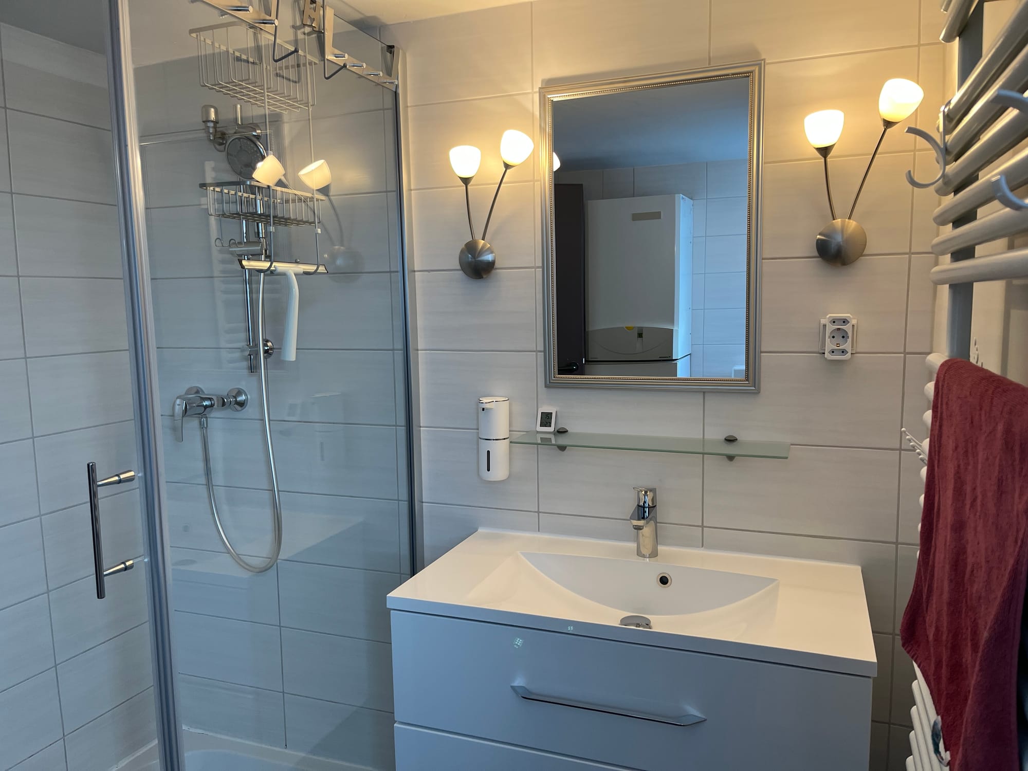 Modernes Badezimmer mit Waschbecken, Dusche und elektrischem Seifenspender.