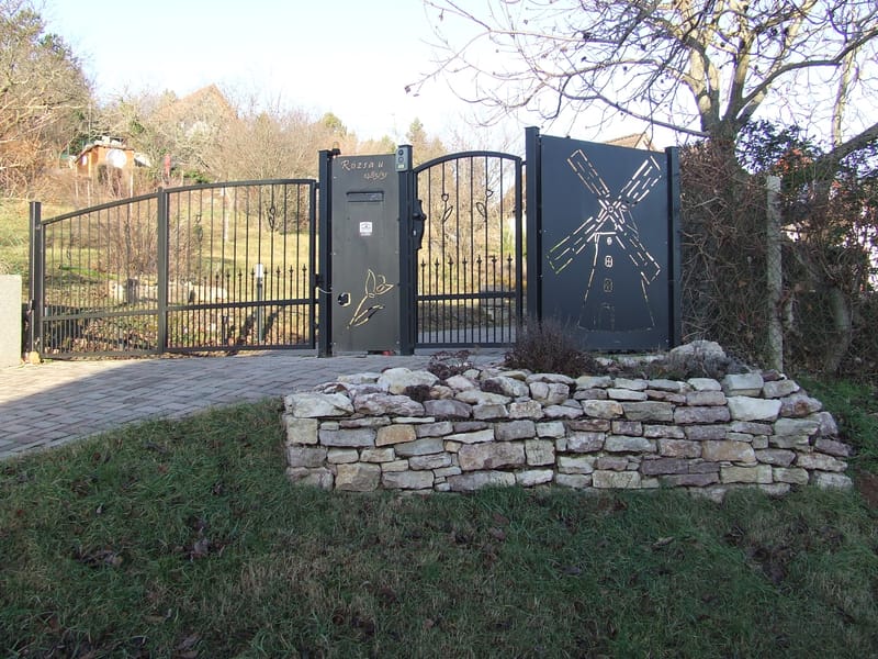 Kovácsoltvas jellegű kis és nagykapu, lézervágott kerítésbetétekkel. Nagykapu motoros távvezérlő telepítéssel. Kiskapu kapunyitóval szerelve.