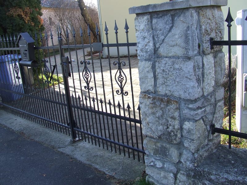 Rakottkő kerítés, kovácsoltvas jellegű kerítéselemekkel, kis és nagykapuval.