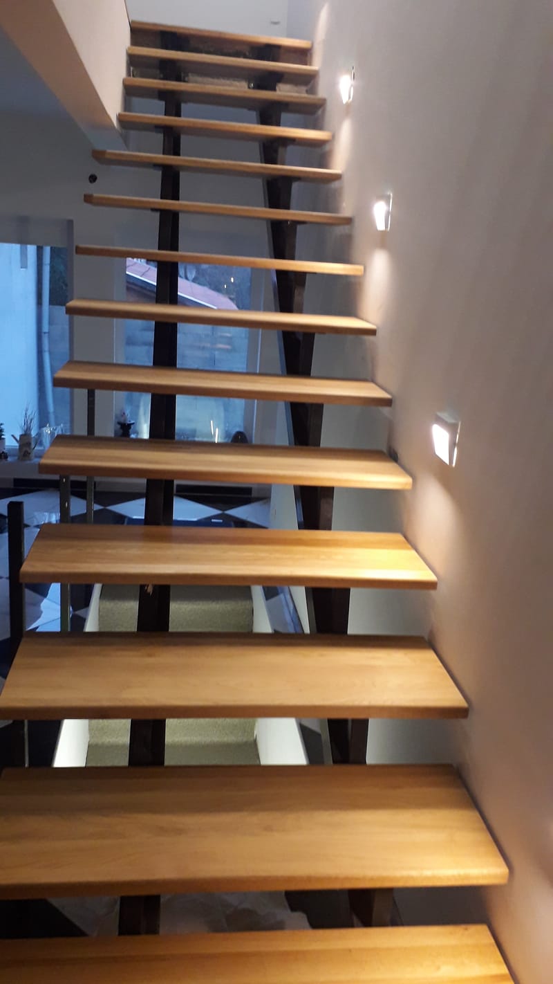 Nyitott, vasvázas lépcső, tölgyfa lépcsőlapokkal, rezgéscsillapítással.