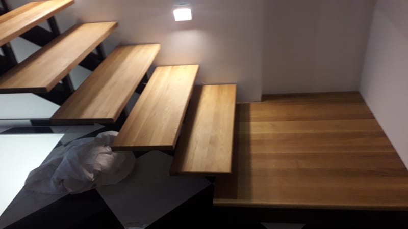 Nyitott, vasvázas lépcső, tölgyfa lépcsőlapokkal, rezgéscsillapítással.